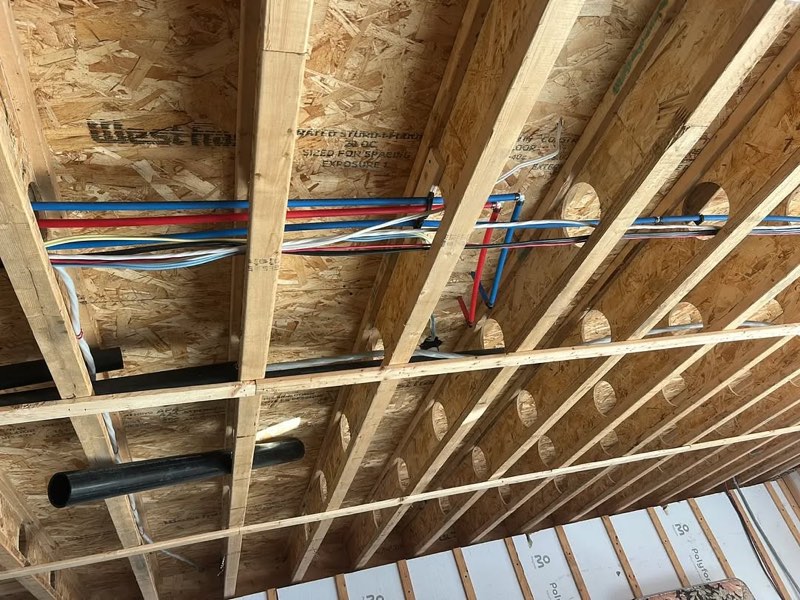 Red and blue PEX lines under the joists of a new house