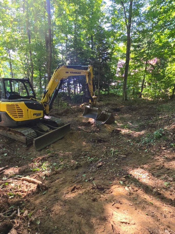 Yellow excavator digging in the woods